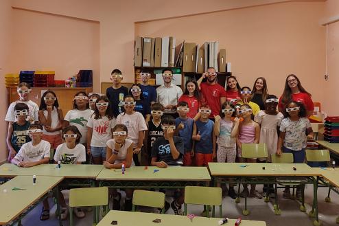 El alcalde, Alejandro Navarro, y el joven estudiante, Alejandro Mena, con los niños que participan en las Colevacaciones posando con las gafas que han realizado para disfrutar del eclipse con todas las garantías 